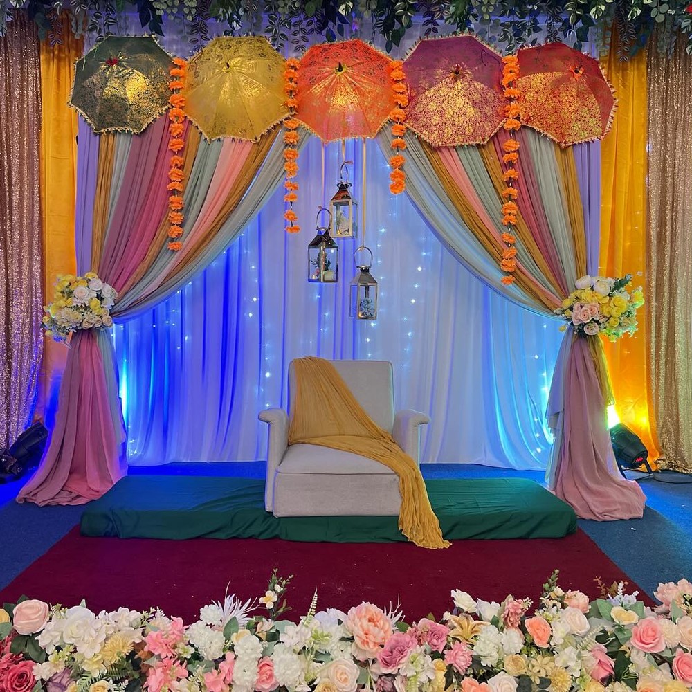 Mehendi stage with floral garland and parasols
